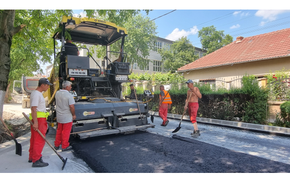 Se asfalteaza strada Bacaului. Muncitorii toarna stratul de binder Se asfalteaza strada Bacaului. Muncitorii toarna stratul de binder